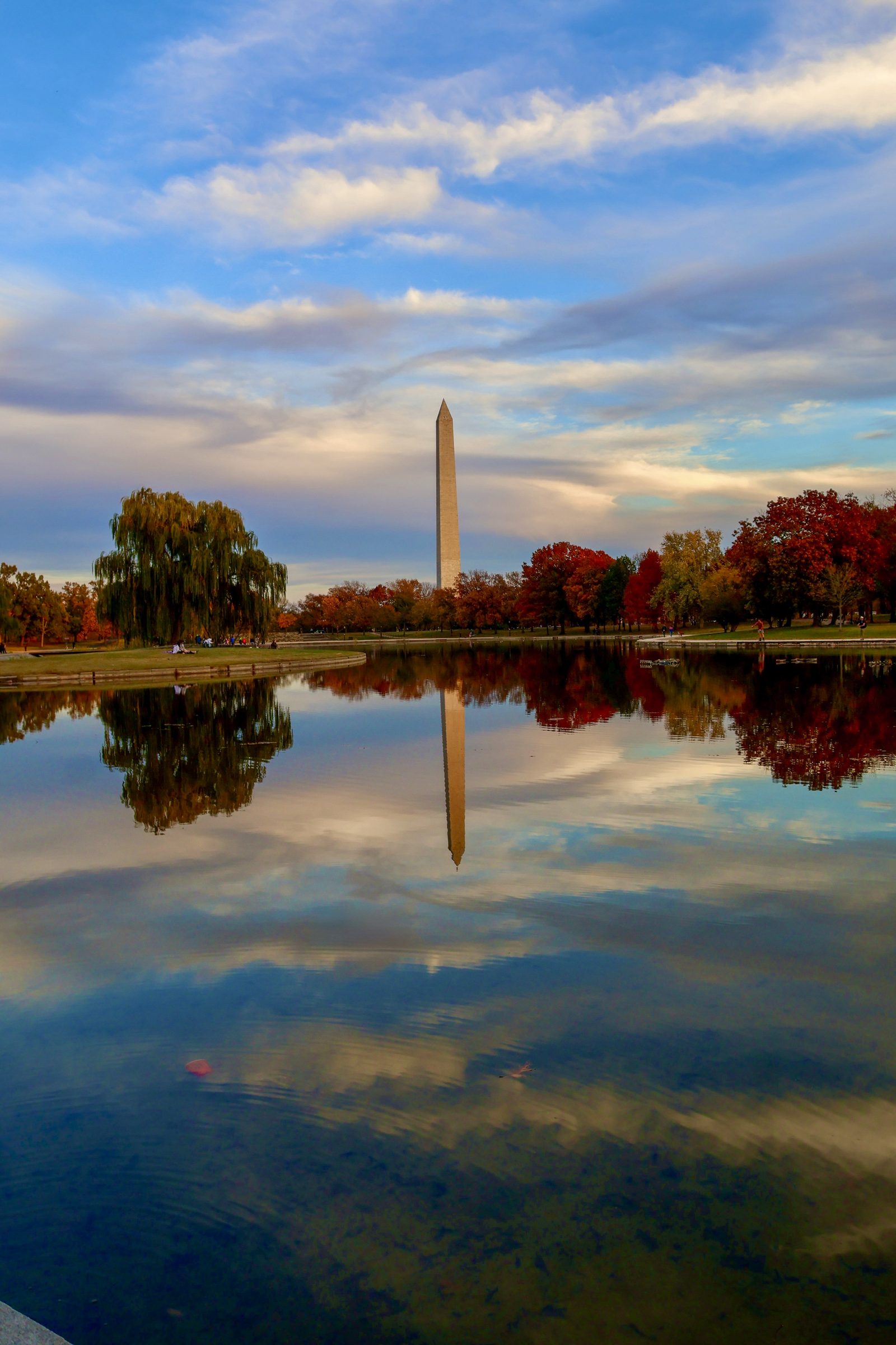 The Washington Monument framed by autumnal trees, reflected sharply in the Constitution Gardens pond.