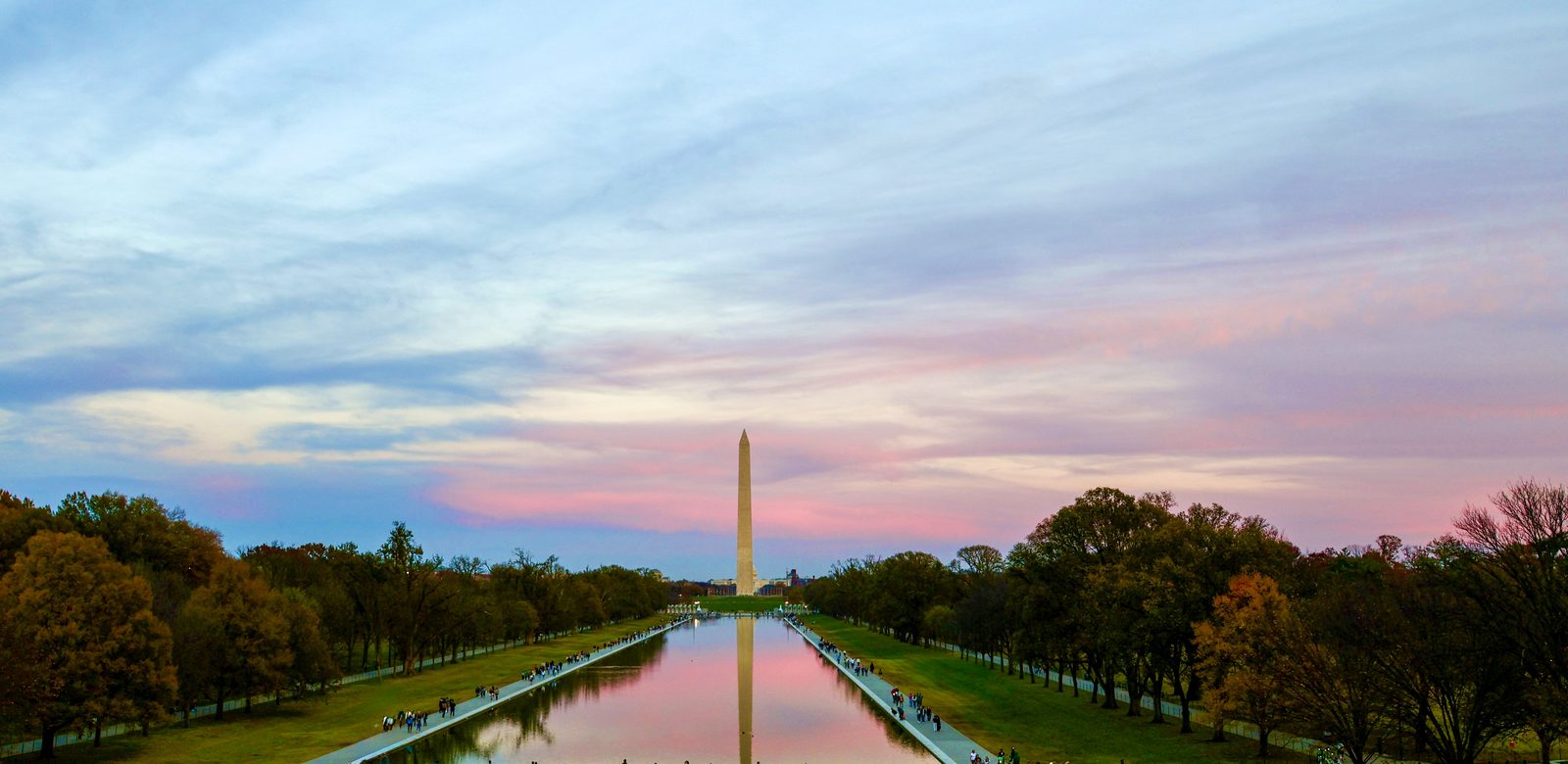 Washington Monument under a pink and lavender dusk sky, reflected in the long Lincoln Memorial Reflecting Pool.