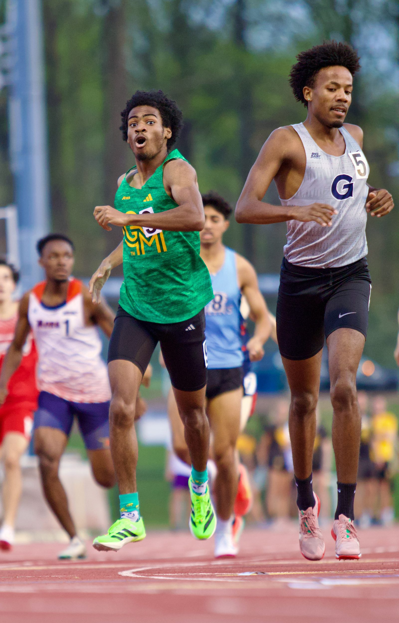 George Mason 800-meter runner mid-race, leaning into a turn alongside a Georgetown athlete.